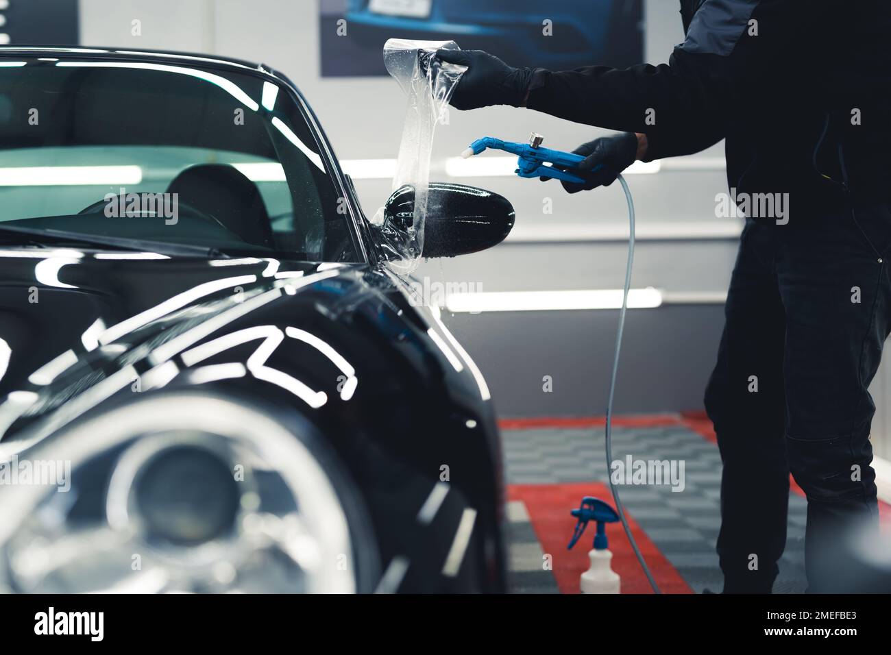 Man wearing black gloves and work uniform applying PPF Paint Protection