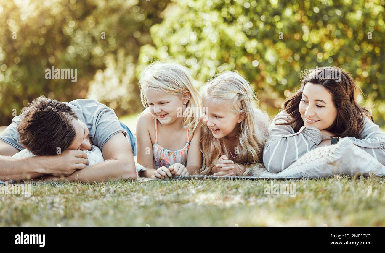 Family, parents and children at park, grass and garden in sunshine. Kids, mom and dad smile on lawn for love, laughing and fun in nature, backyard and Stock Photo