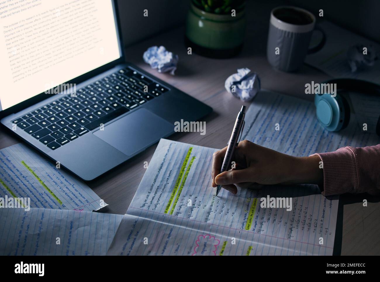 Student, hands and writing notes at night with laptop for research