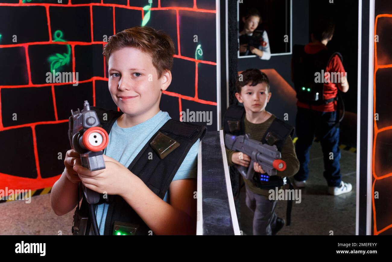 boy aiming laser gun at other players during lasertag game Stock Photo