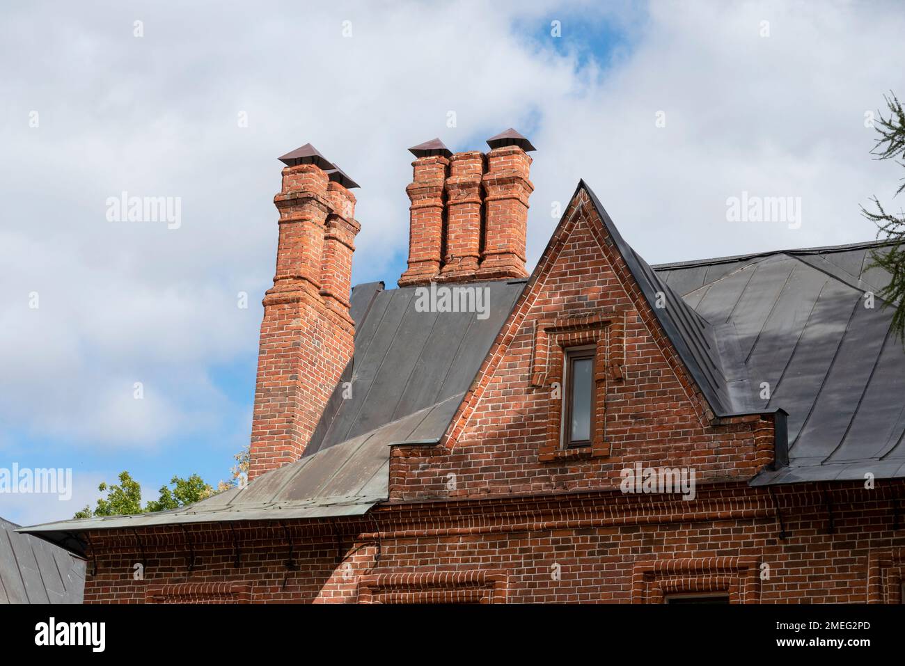 Red roof tiles with a red brick chimney on a blue sky background. Old ...