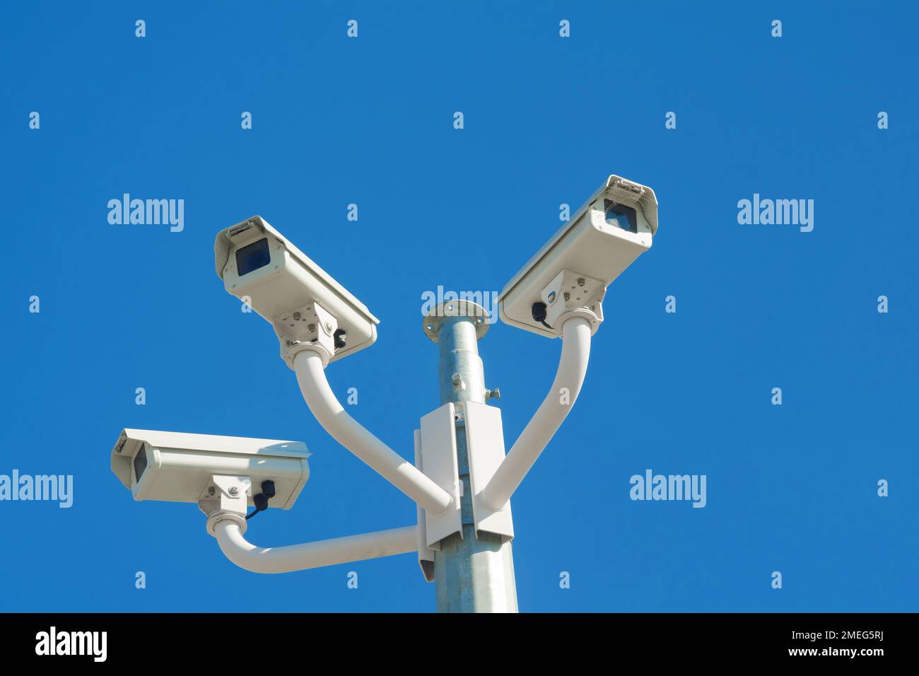 Three CCTV surveillance cameras isolated against blue sky Stock Photo