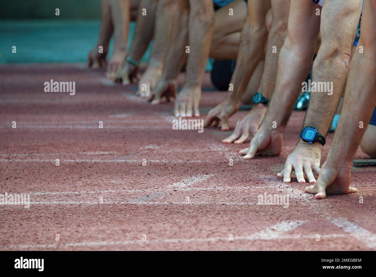 Athletes at the sprint start line in track and field. Hands on the
