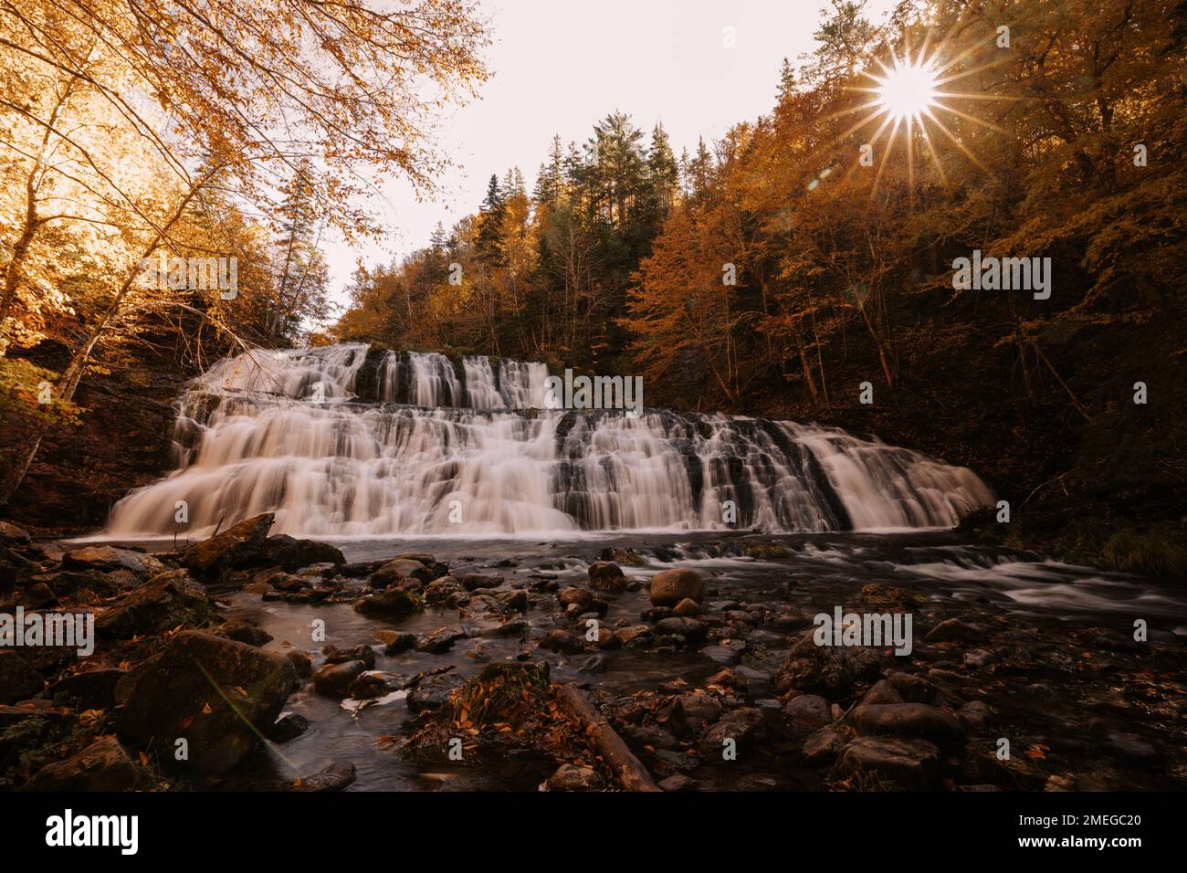A scenic view of a waterfall flowing down the rocks in a forest on a ...