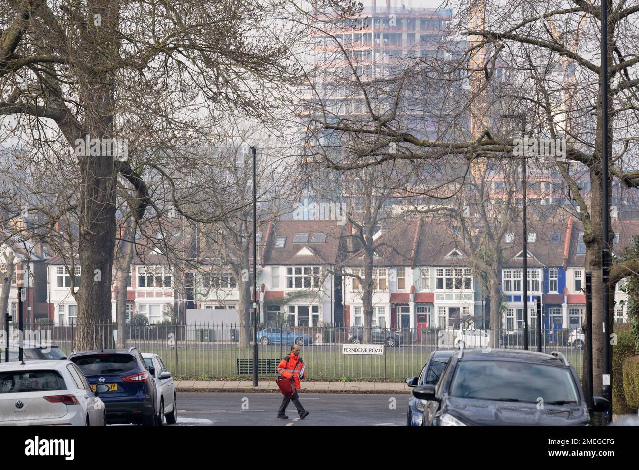 A Royal Mail postman delivers postal items on Ferndene Road where a new high-rise development at Higgs yard is seen under construction in Loughborough Junction in Lambeth, on 23rd January 2023, in London, England. Stock Photo