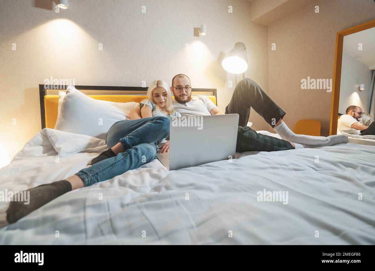 Young couple lying on couch at home looking at laptop. Stock Photo
