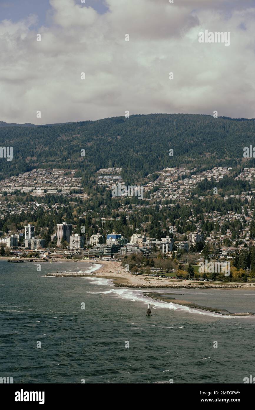A vertical aerial view of seaside cityscape and mountain forests Stock ...
