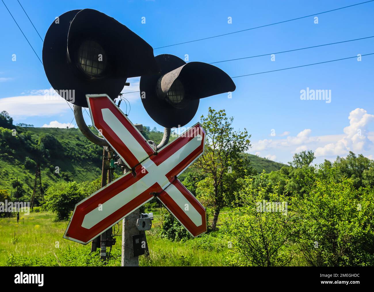 stop sign in front of a railway crossing on a background of blue sky with clouds Stock Photo