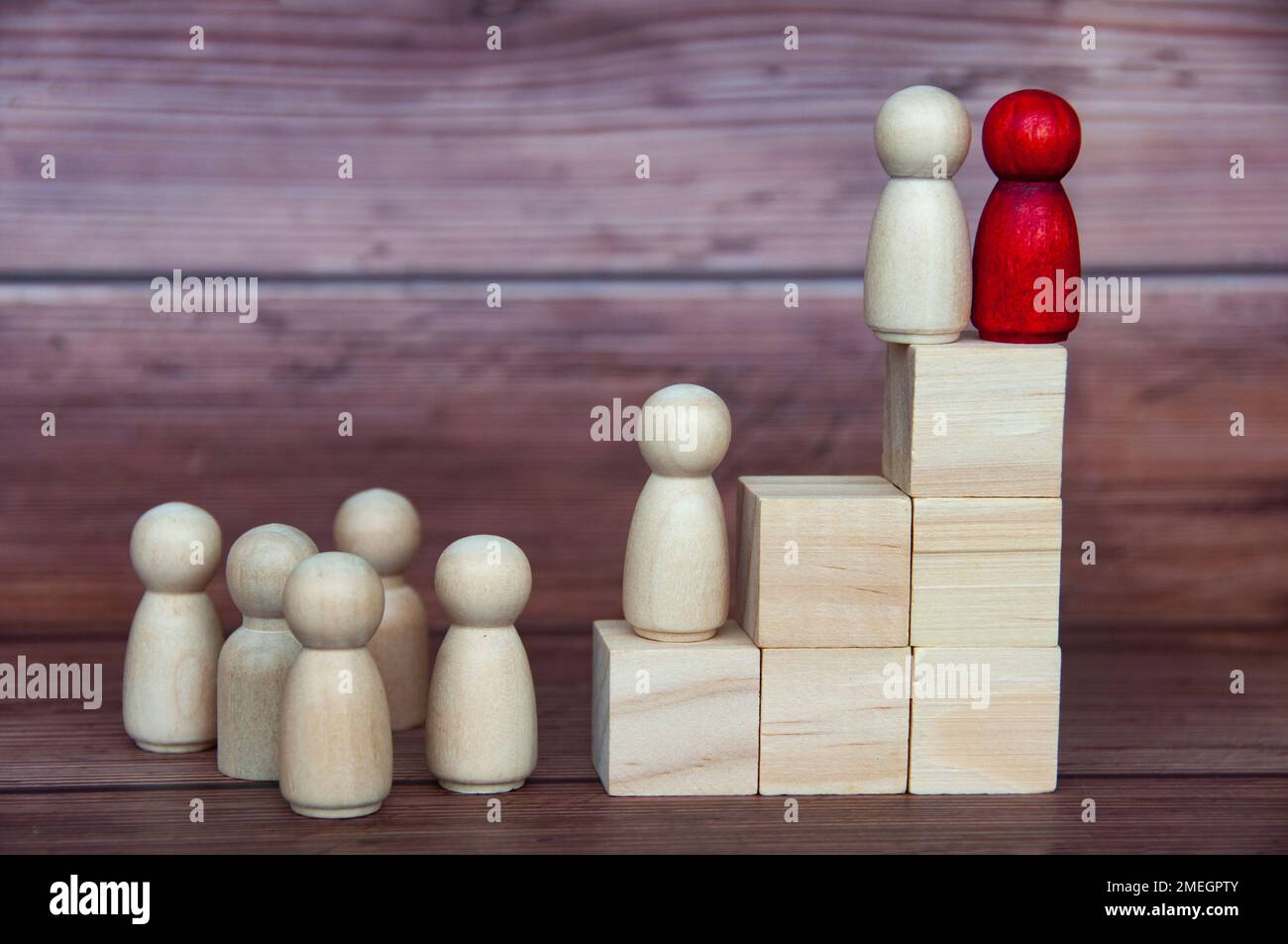 Leadership concept - two wooden figures on wooden blocks with other figures reaching to the top. Leadership concept. Stock Photo