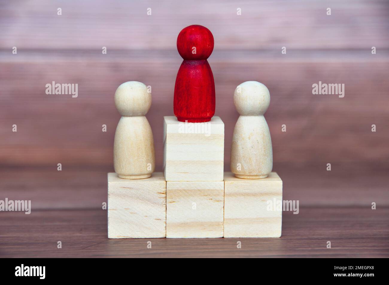 Winning concept - Red figure in the middle of other figure on wooden blocks. Stock Photo
