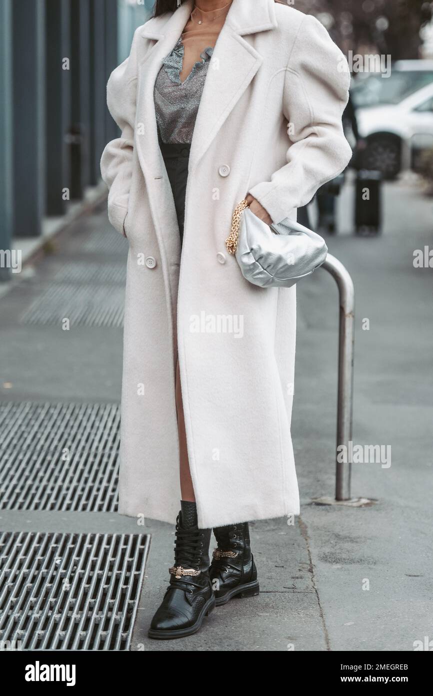 Milan, Italy - February 24, 2022: Female in beige long coat with silver handbag. Stock Photo