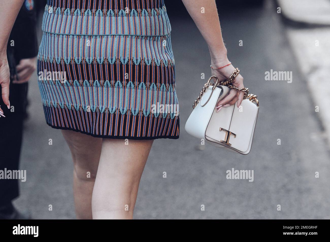 Milan, Italy - February 24, 2022: Back view of Woman in patterned short dress with white chain bag. Stock Photo