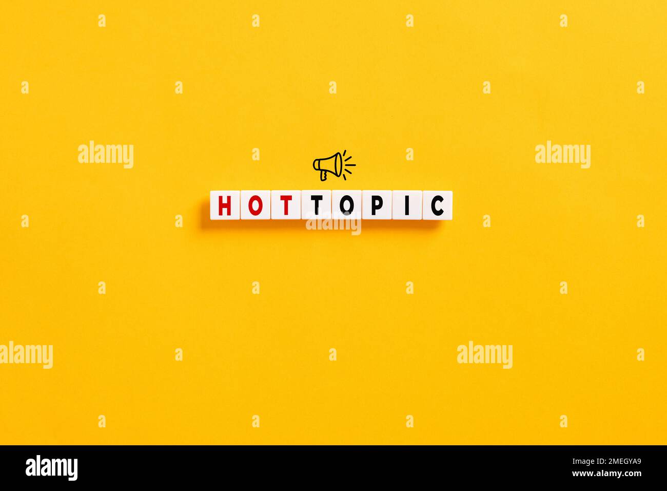 White letter blocks on yellow background with the word hot topic and a megaphone symbol. Popular topics and latest discussion trends. Stock Photo