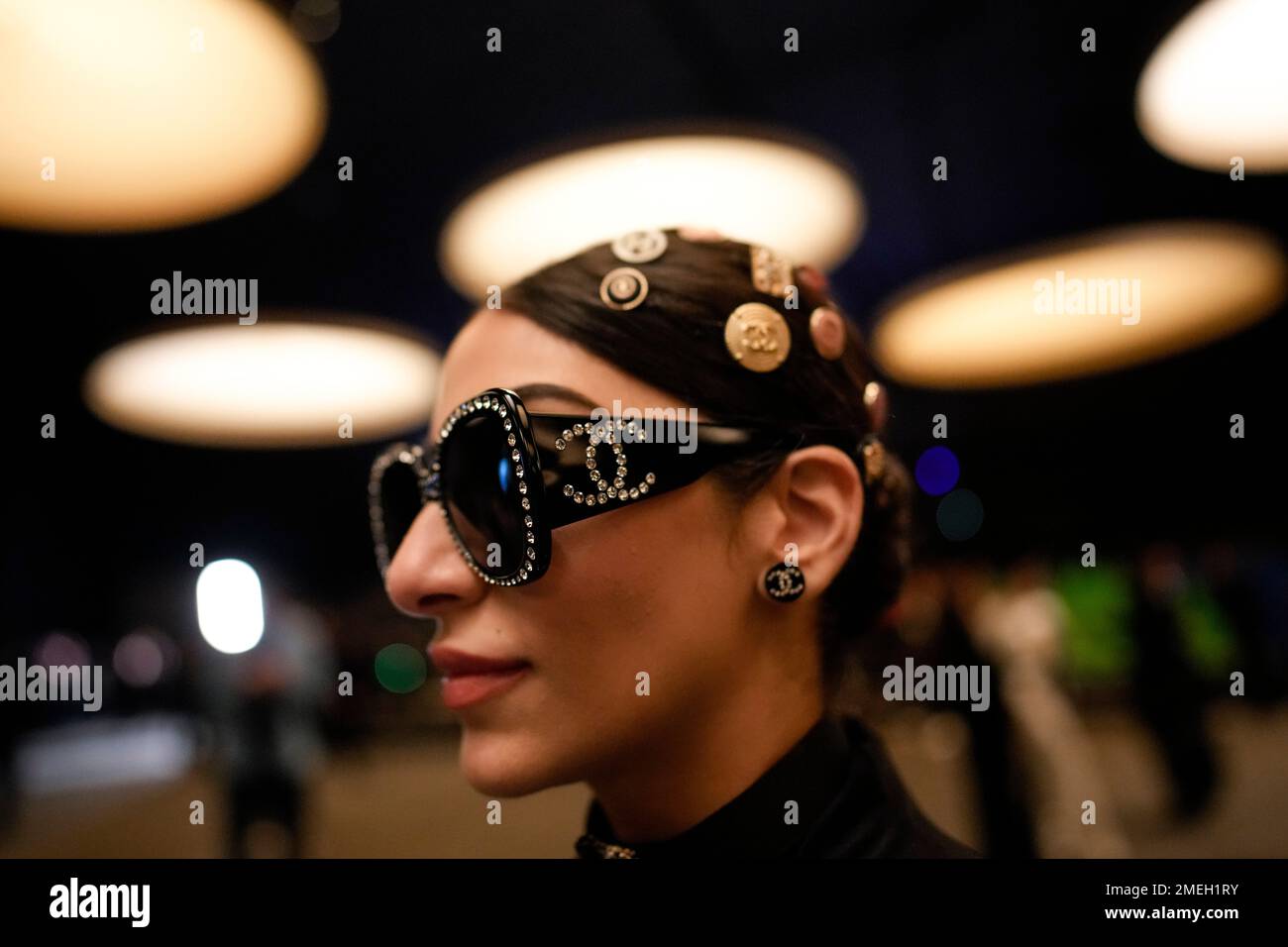 An audience member with Chanel logos on their hat and sunglasses is seen  arriving at the Chanel Haute Couture Spring-Summer 2023 collection  presented in Paris, Tuesday, Jan. 24, 2023. (AP Photo/Christophe Ena