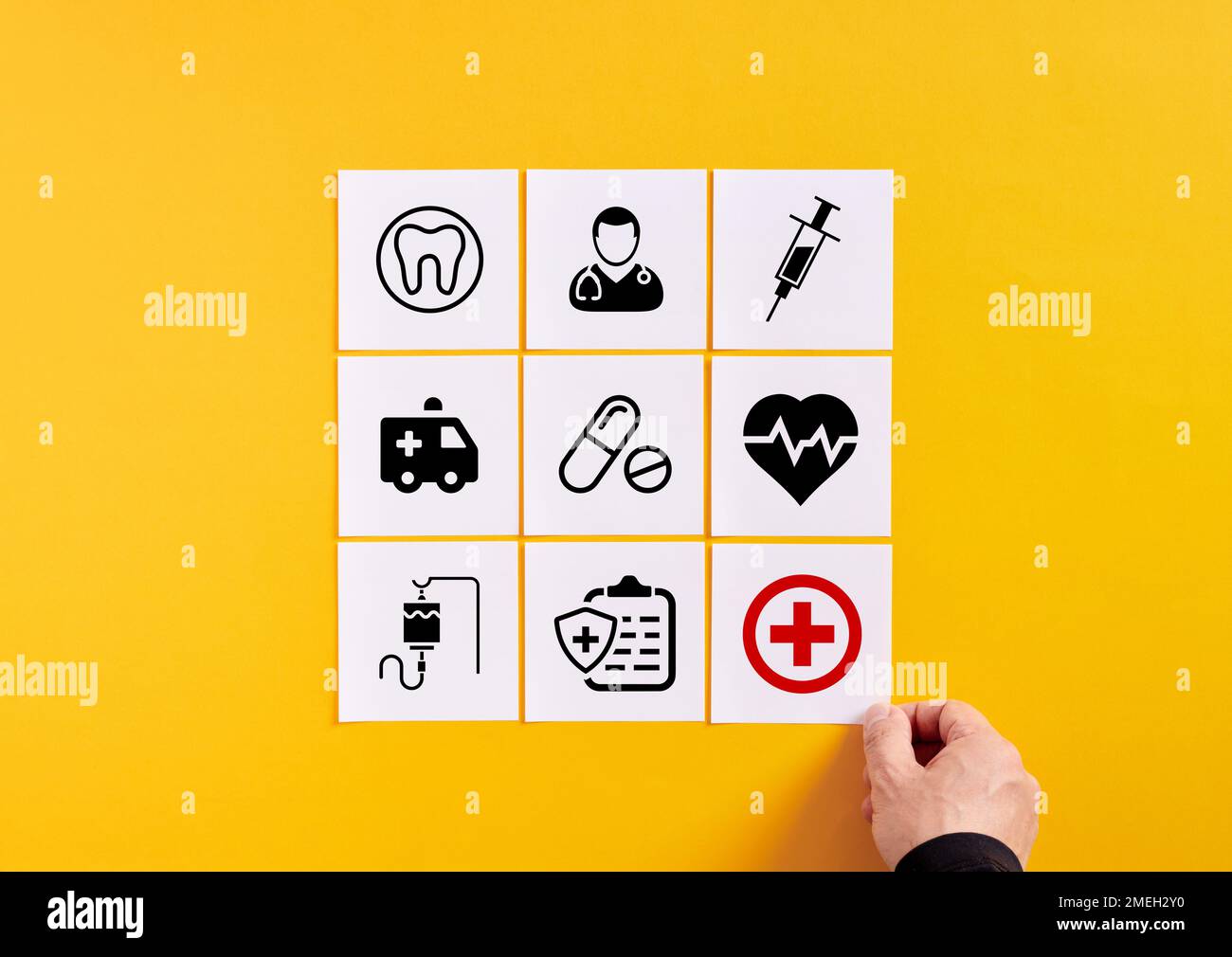 Health care services and medical attention concept. Hand arranges note papers with healthcare symbols. Stock Photo