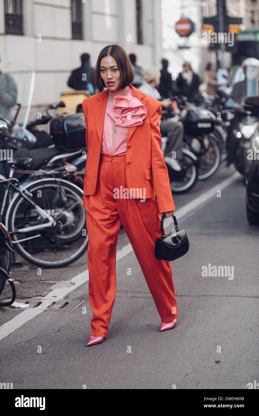 Milan, Italy - February 25, 2022: Female wearing a red fancy suit, black handbag and pink elegant shoes. Stock Photo