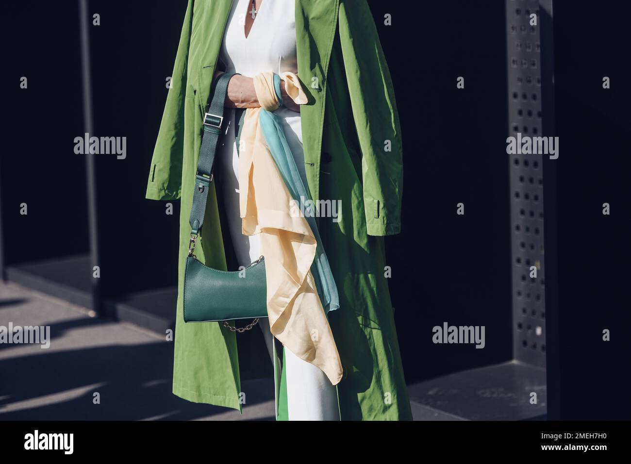 Milan, Italy - February 25, 2022: Female wearing a green coat, white dress, matching green bag and green high heels boots. Stock Photo