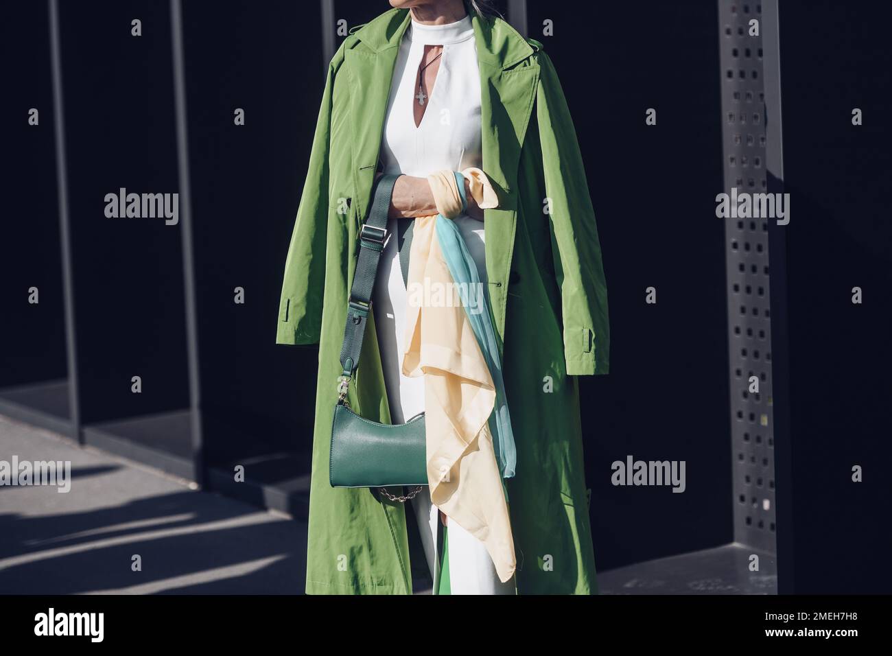Milan, Italy - February 25, 2022: Female wearing a green coat, white dress, matching green bag and green high heels boots. Stock Photo