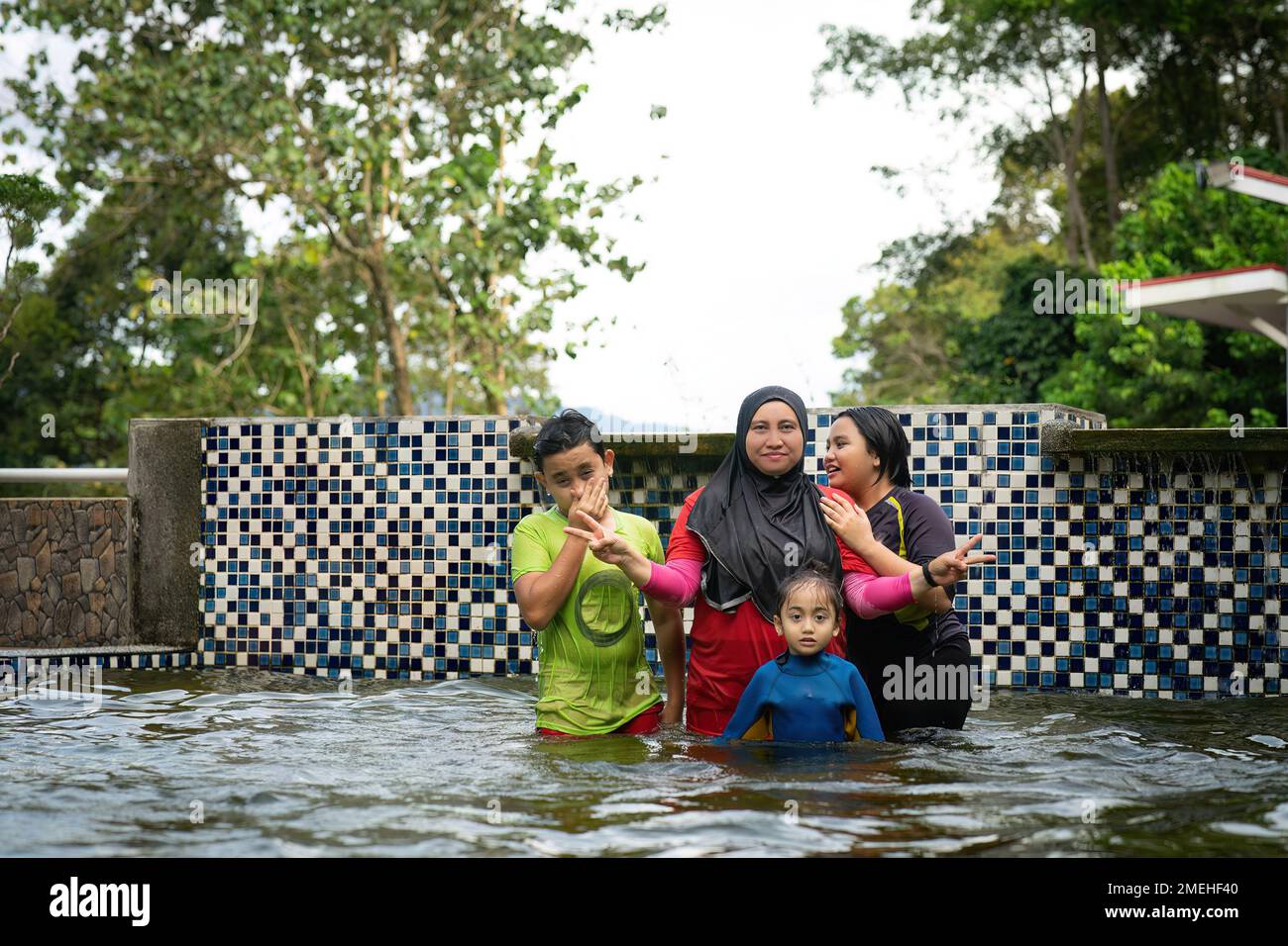 Swimming in the pool with a happy family Mother wearing hijab with