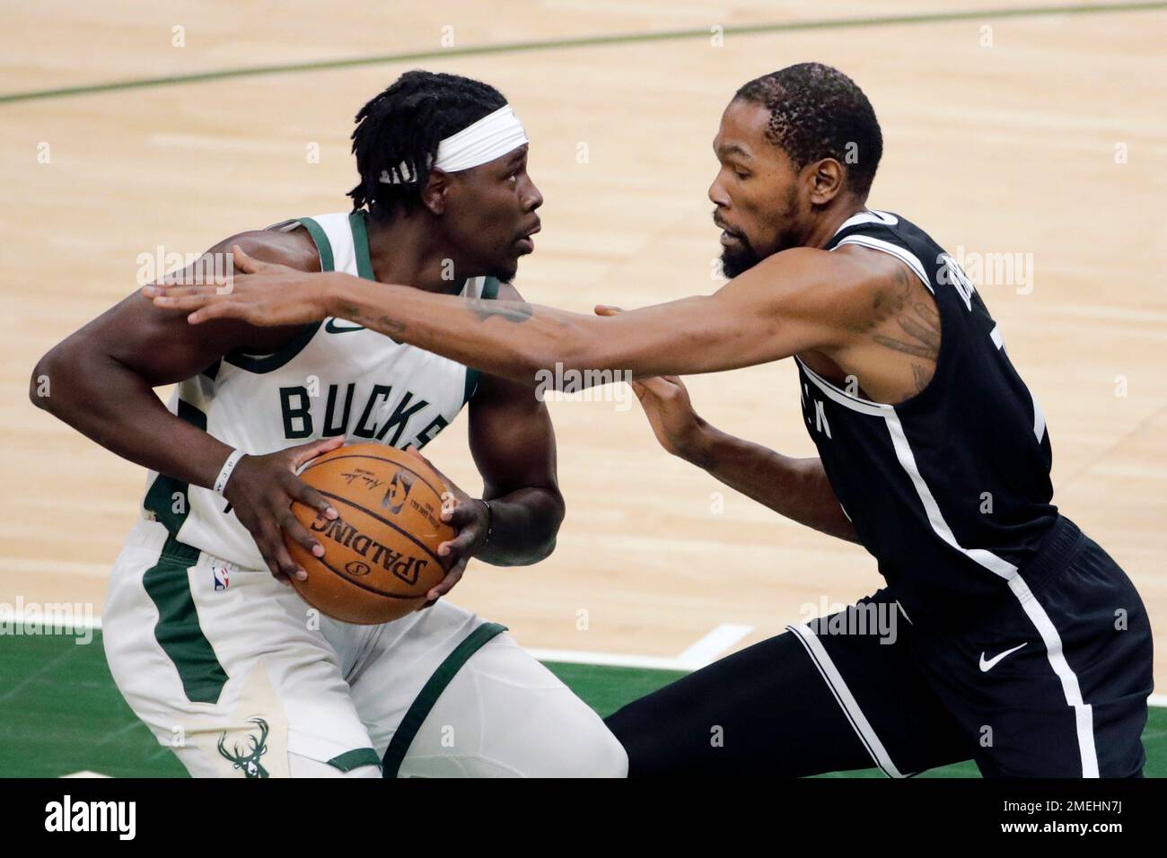 Milwaukee Bucks' Jrue Holiday, left, drives to the basket against Brooklyn Nets' Kevin Durant