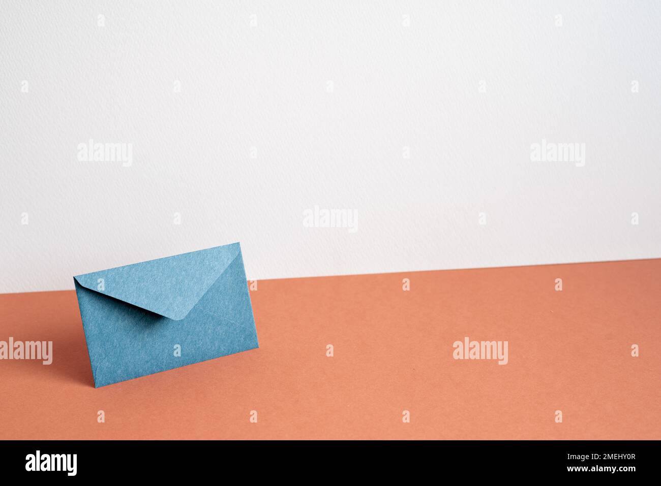 Navy color envelope on red table. white wall background. minimalism, copy space Stock Photo