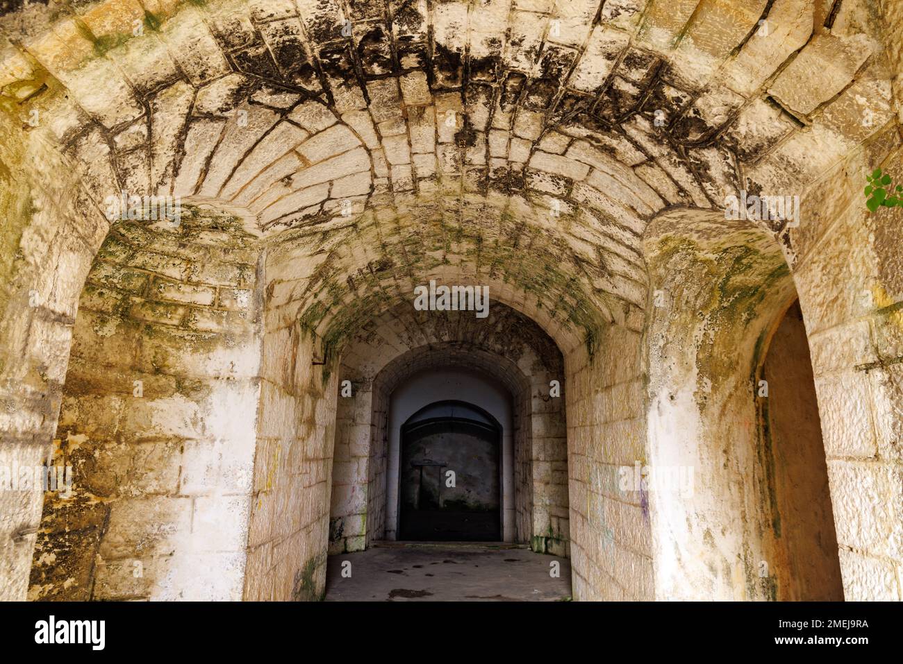 Concrete old walls of a dark empty narrow corridor of the ancient historical fort Gorazda in warm sunny touristic Montenegro Stock Photo