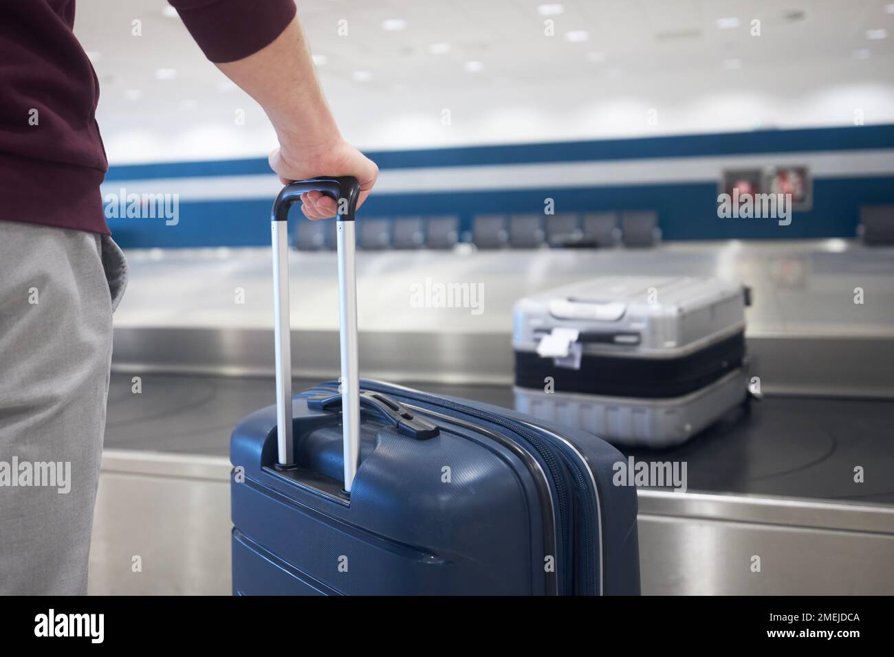 Traveling by airplane. Passenger holding his suitcase in baggage claim