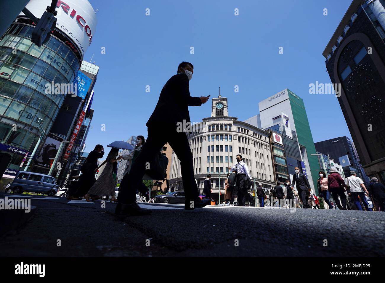 People wearing protective masks to help curb the spread of the coronavirus  walk through a crosswalk at the beginning of Japan's "Golden Week" holidays  Friday, April 30, 2021, at Ginza shopping district