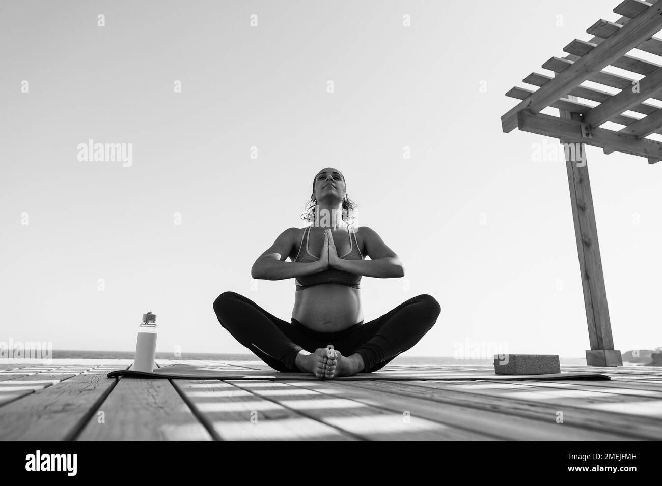 Young pregnant woman doing yoga meditation outdoor - Focus on face - Black and white editing Stock Photo