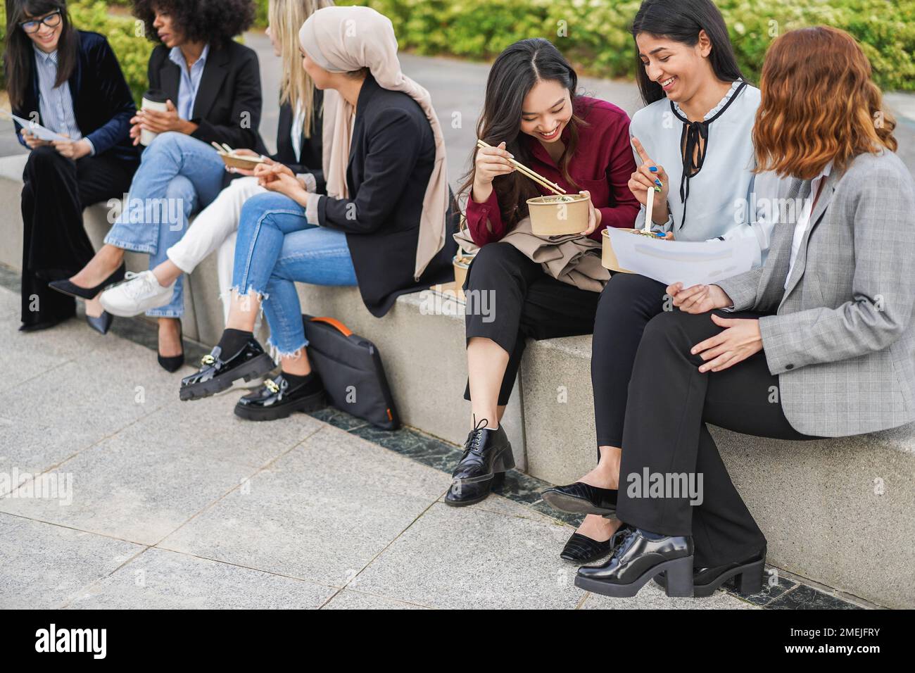 Multiethnic business women doing lunch break outdoor from office building - Focus on asian girl hand Stock Photo