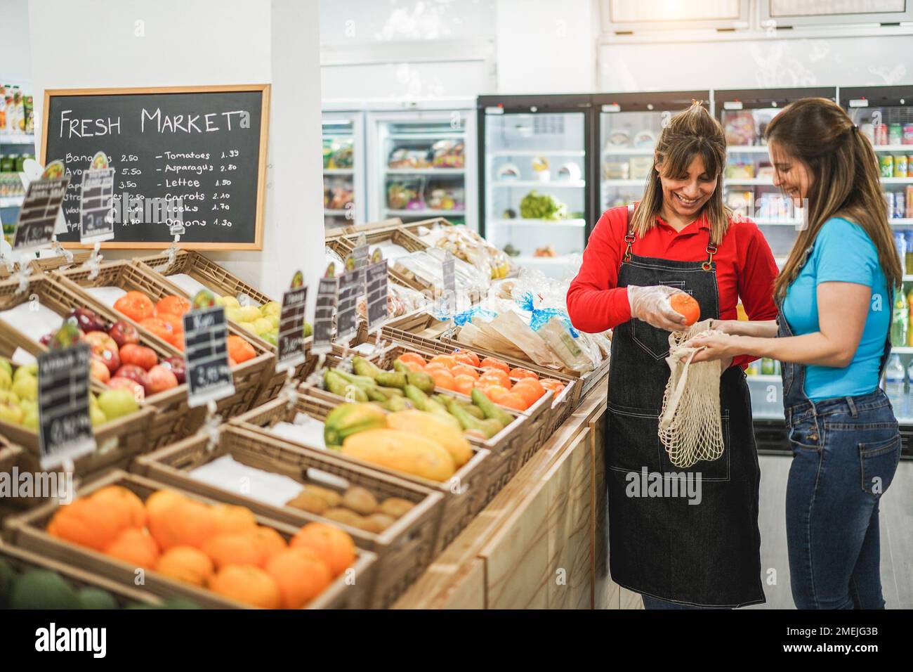 Female customer buying organic food fruits inside eco fresh market - Soft focus on left woman face Stock Photo