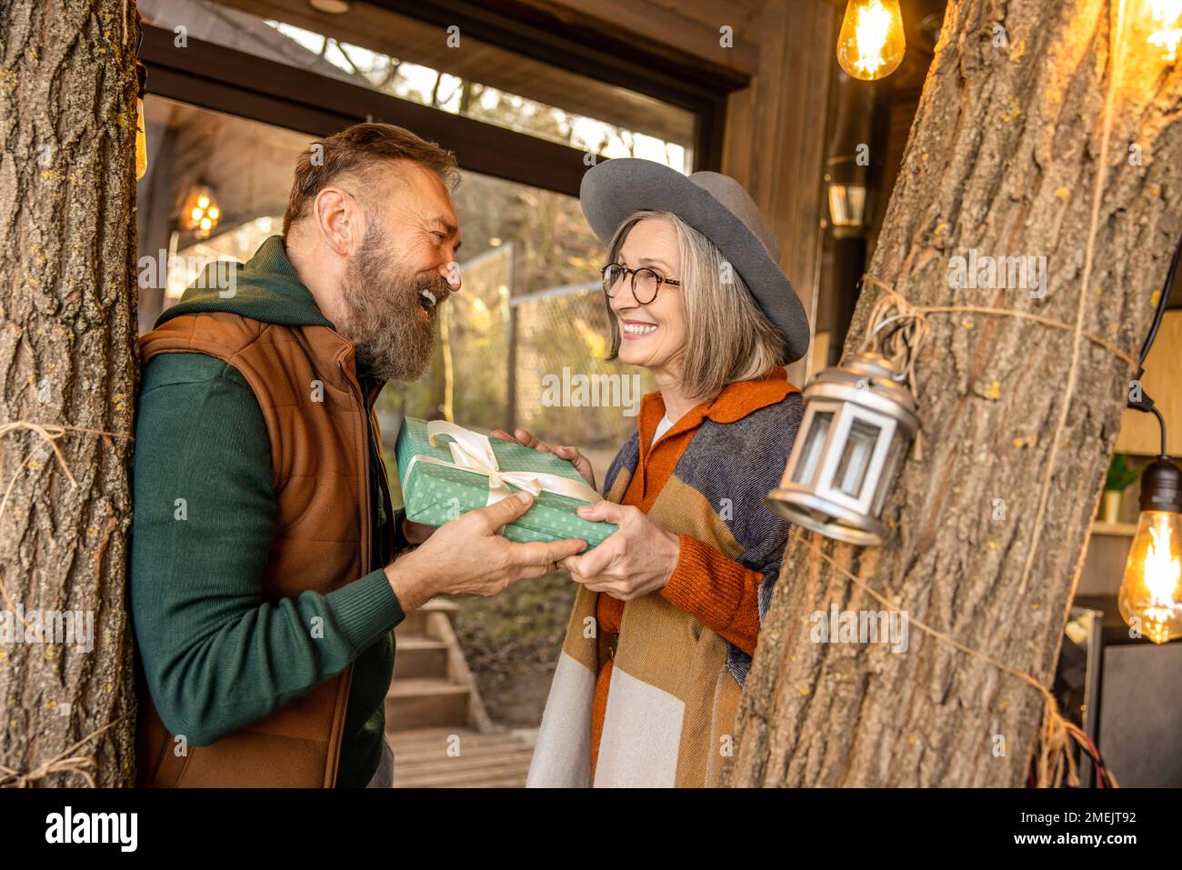 Smiling man giving a gift to his wife and looking happy Stock Photo