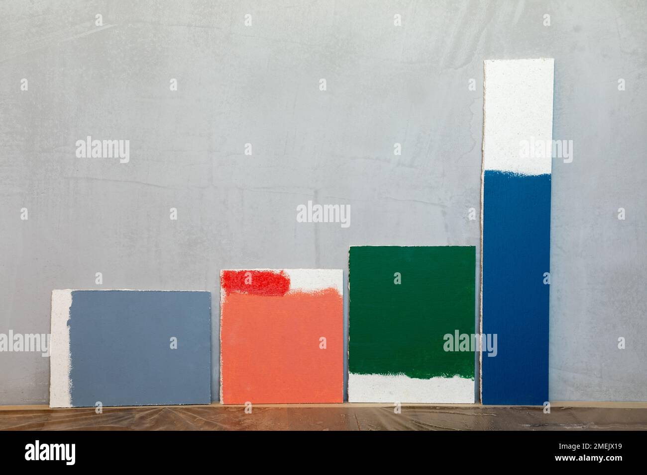 Grey red green and blue color samplers at blank gypsum plaster wall. Choosing wall paint color during house renovation Stock Photo