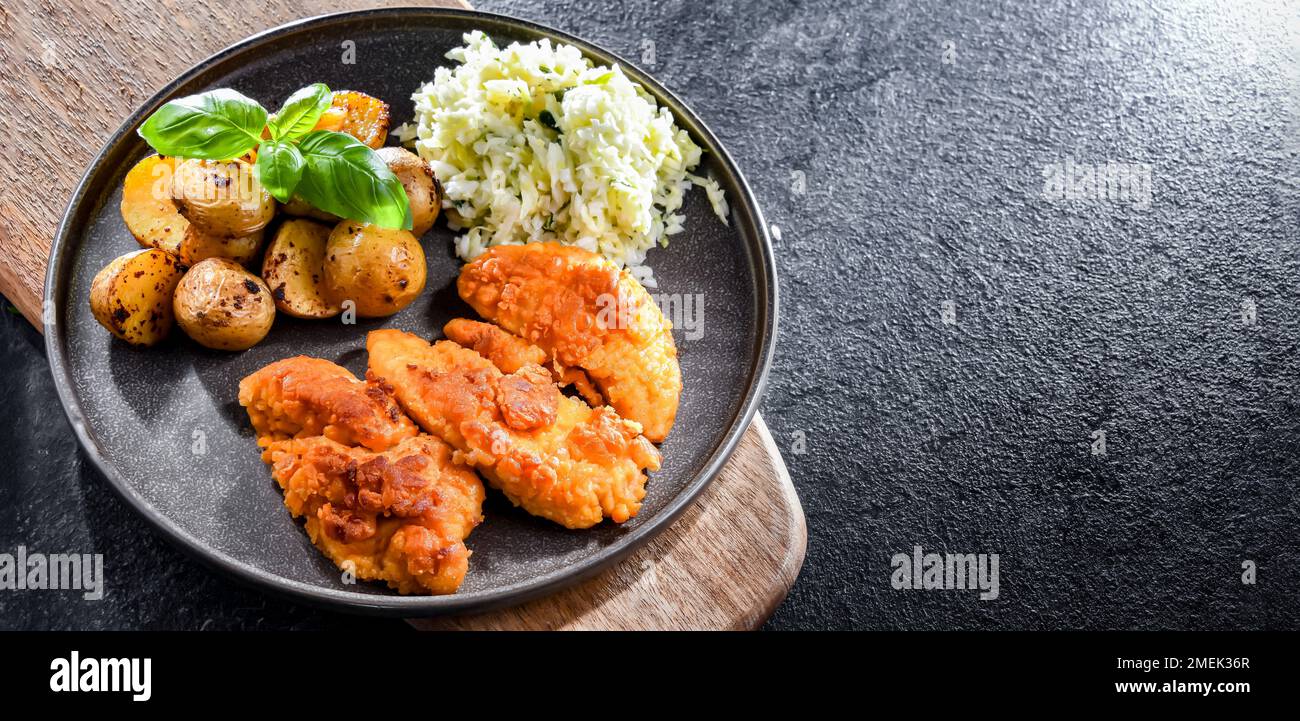 Breaded chicken cutlets served with potatoes and cabbage. Stock Photo