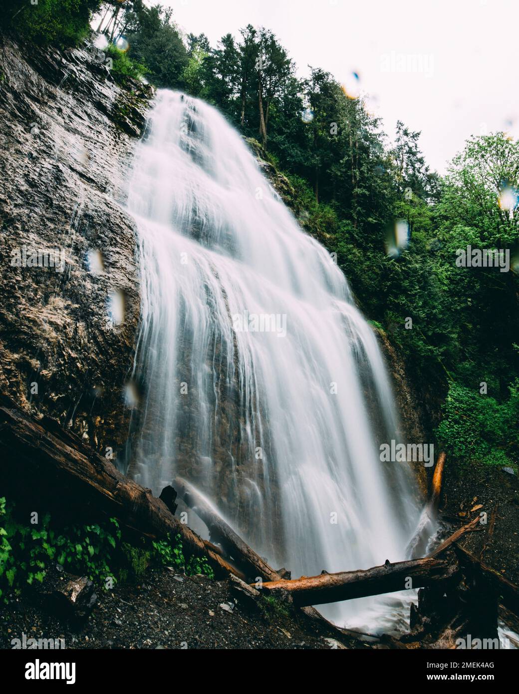 A vertical long exposure of a waterfall flowing down the cliff into a ...