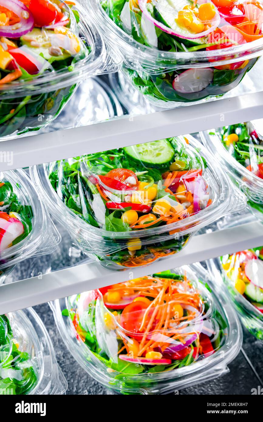 Plastic boxes with pre-packaged vegetable salads, put up for sale in a commercial refrigerator Stock Photo