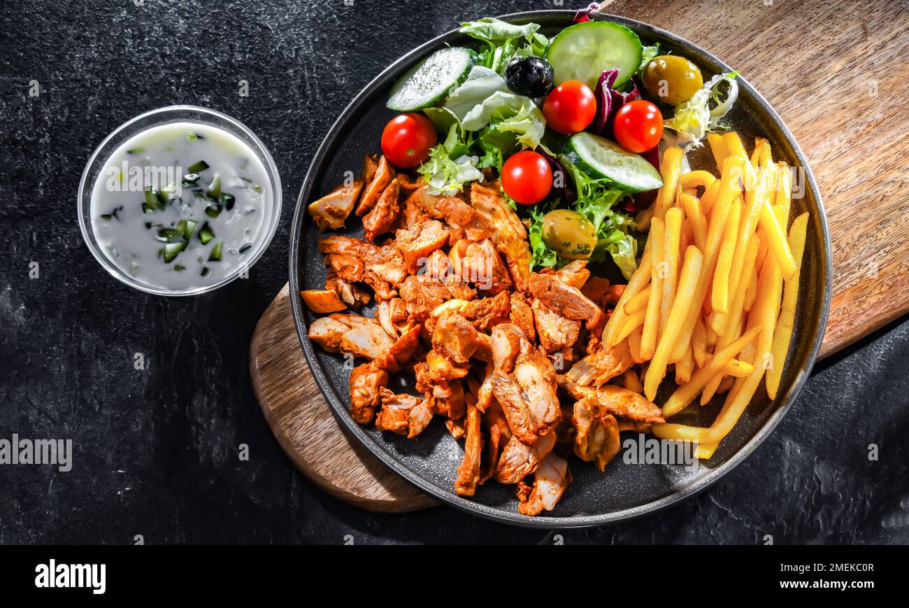 Kebab served with french fries, vegetable salad and tzatziki Stock Photo