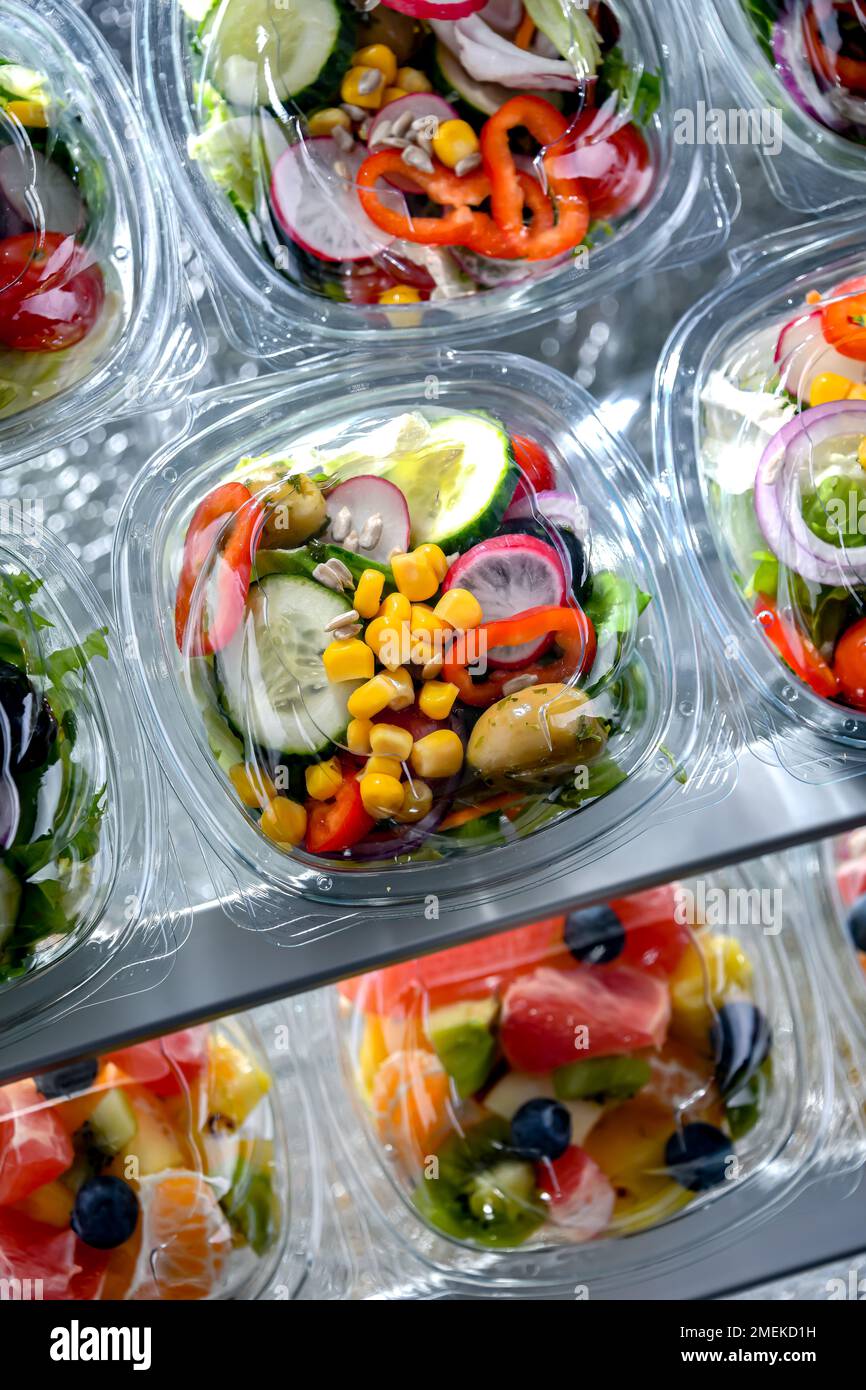 Plastic boxes with pre-packaged vegetable salads, put up for sale in a commercial refrigerator Stock Photo