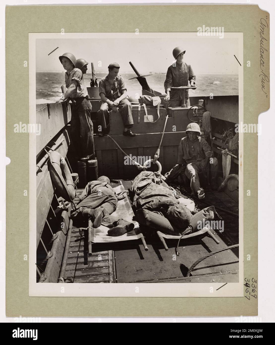A Coast Guard coxswain speeds a landing craft ambulance, carrying wounded soldiers from the battle-scarred beach of Eniwetok to a transport vessel offshore. His crew stands ready to assist with the transfer of the injured to safety. Stock Photo