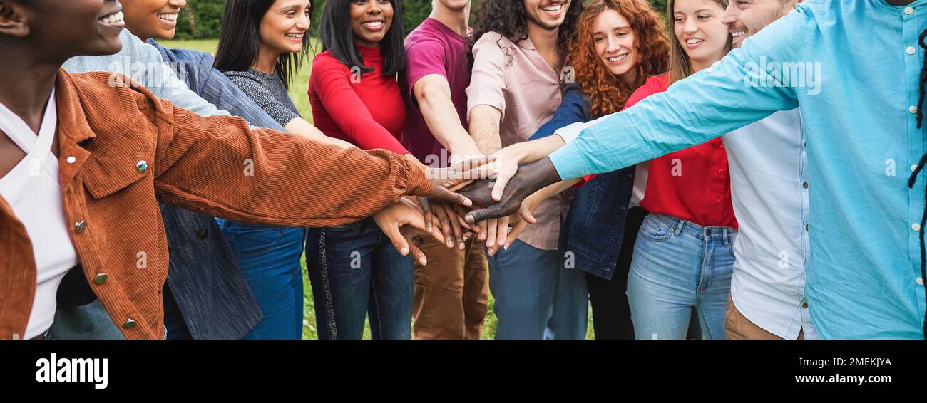 Young diverse team having fun stacking hands outdoor - Focus on hands Stock Photo