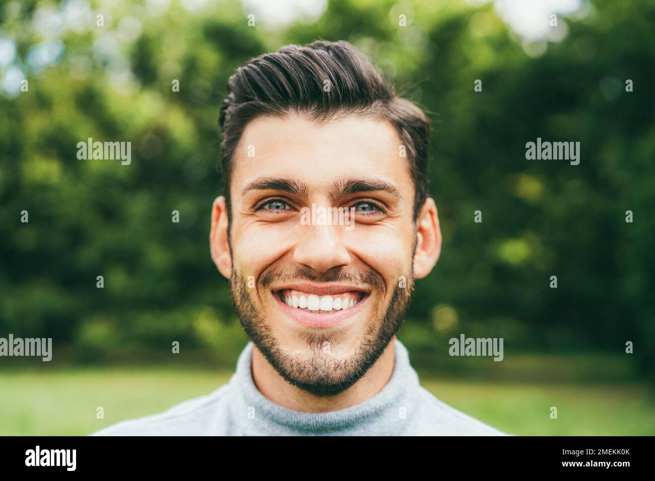 Young happy man looking at camera outdoor - Main focus on nose Stock Photo