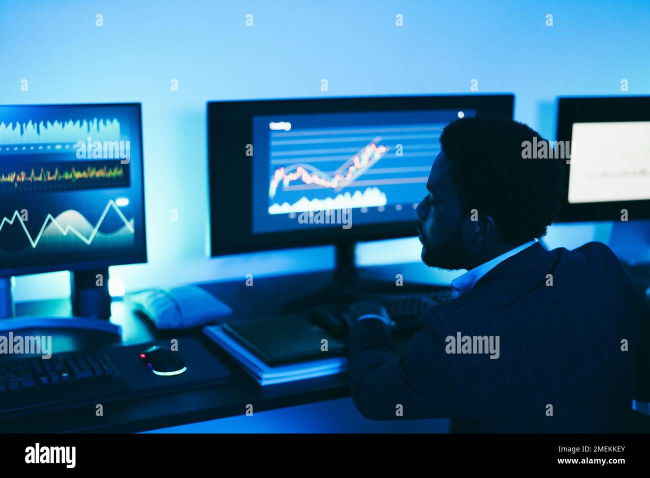 African trader working inside office at night time - Main focus on man ear Stock Photo