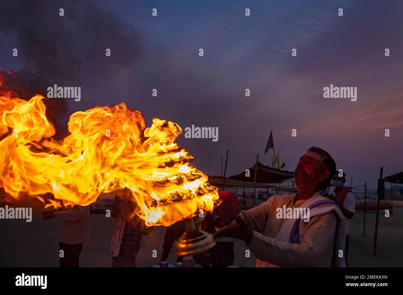 A Hindu priests rotate traditional oil lamps in circular movements as