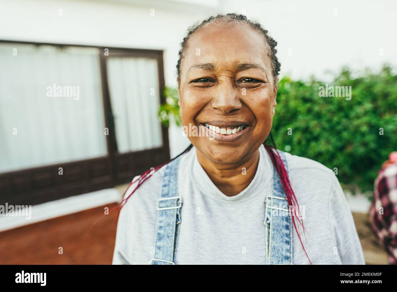 Happy african senior woman smiling on camera with house background - Main focus on nose Stock Photo