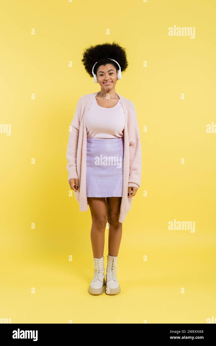 full length of cheerful african american woman in cardigan and wireless ...