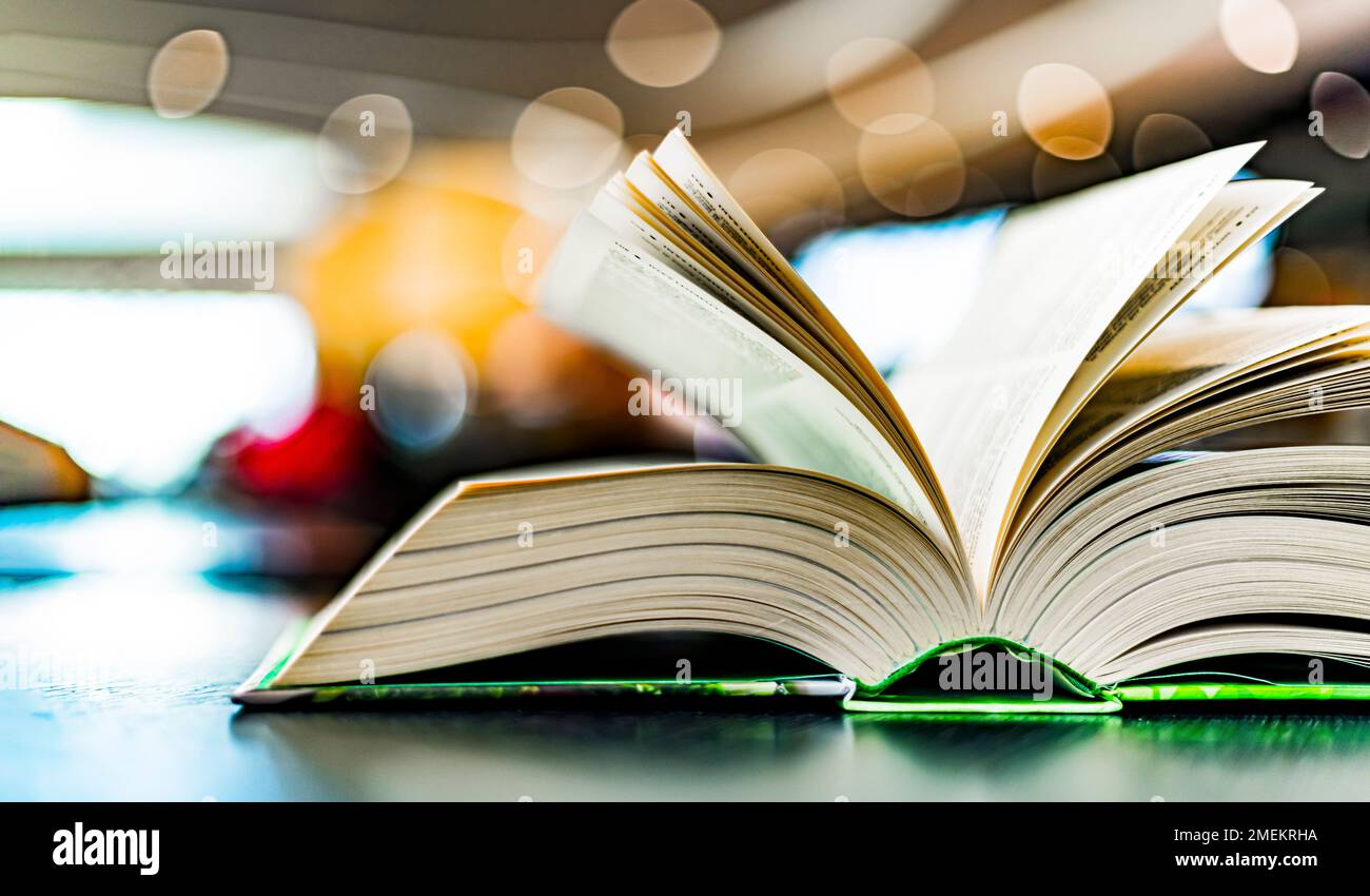 An open hardcover book on a table in a public library Stock Photo
