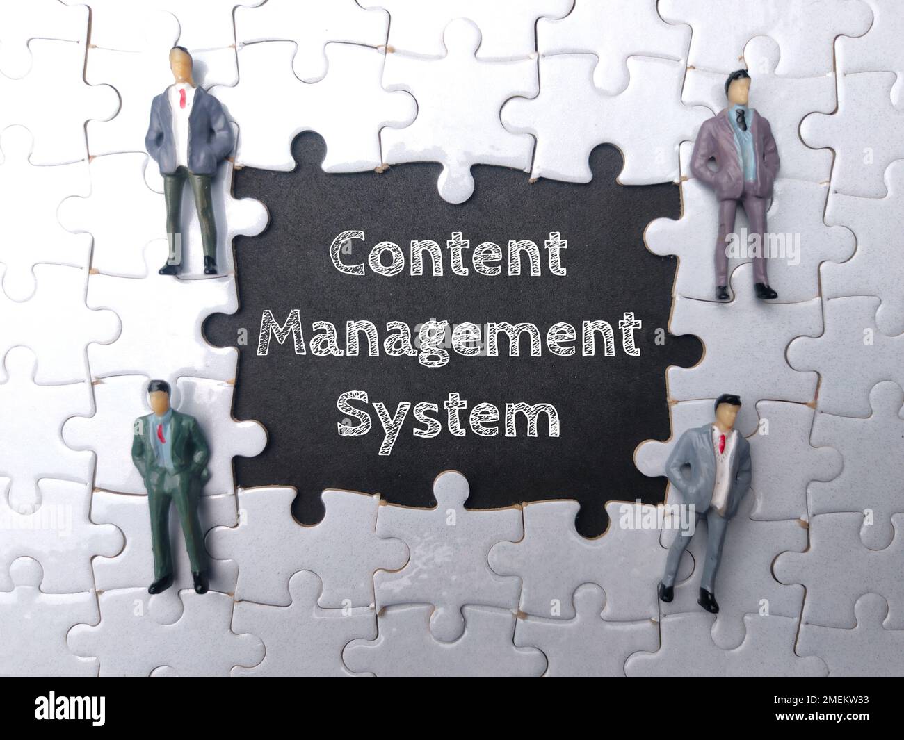 Miniature people with the word CONTENT MANAGEMENT SYSTEM on black background. Stock Photo