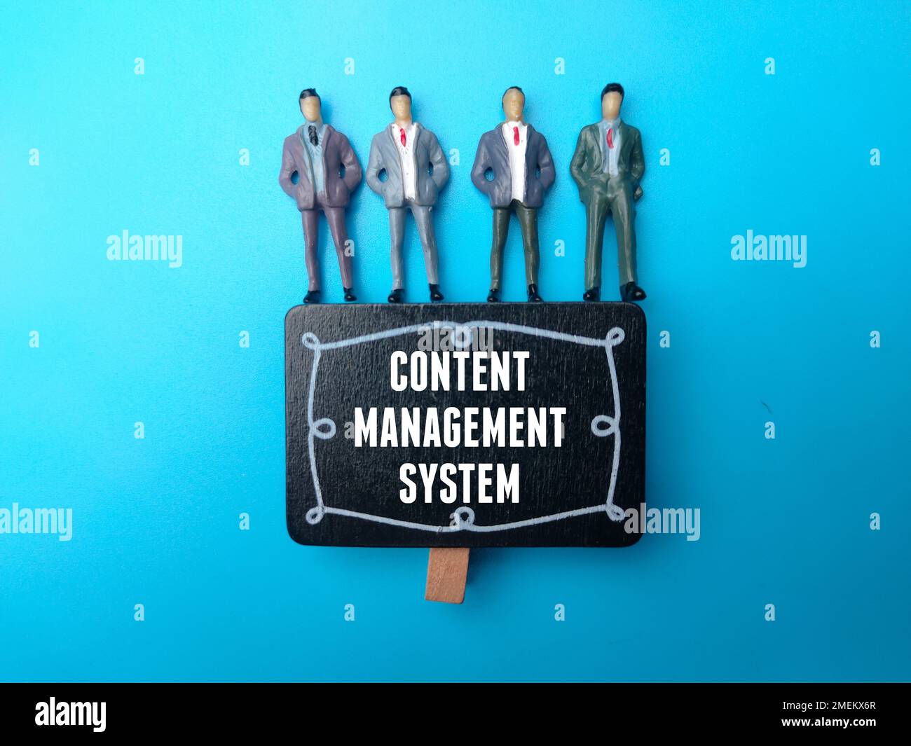 Miniature people with the word CONTENT MANAGEMENT SYSTEM on blue background. Stock Photo