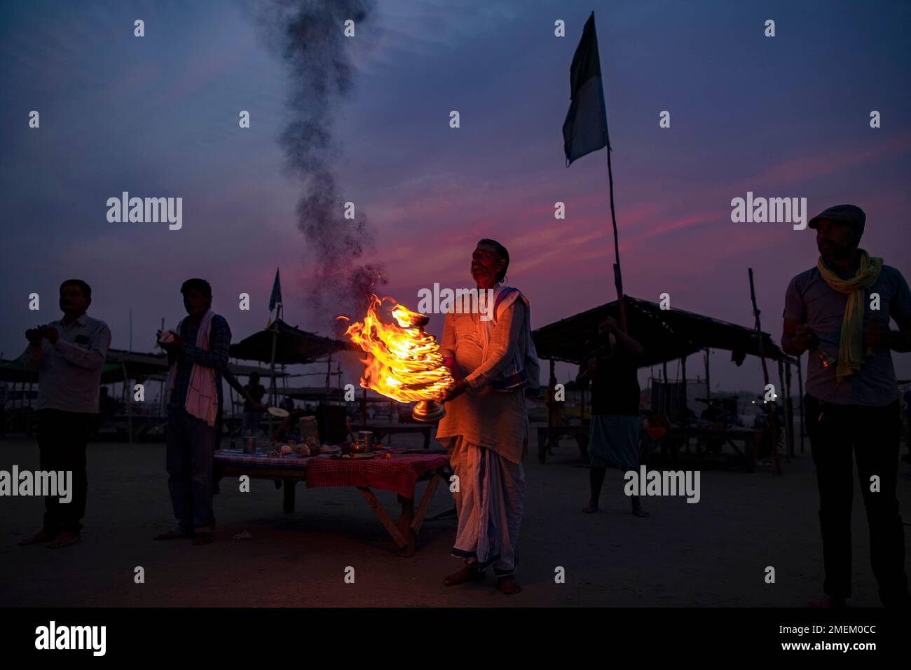 A Hindu priests rotate traditional oil lamps in circular movements as
