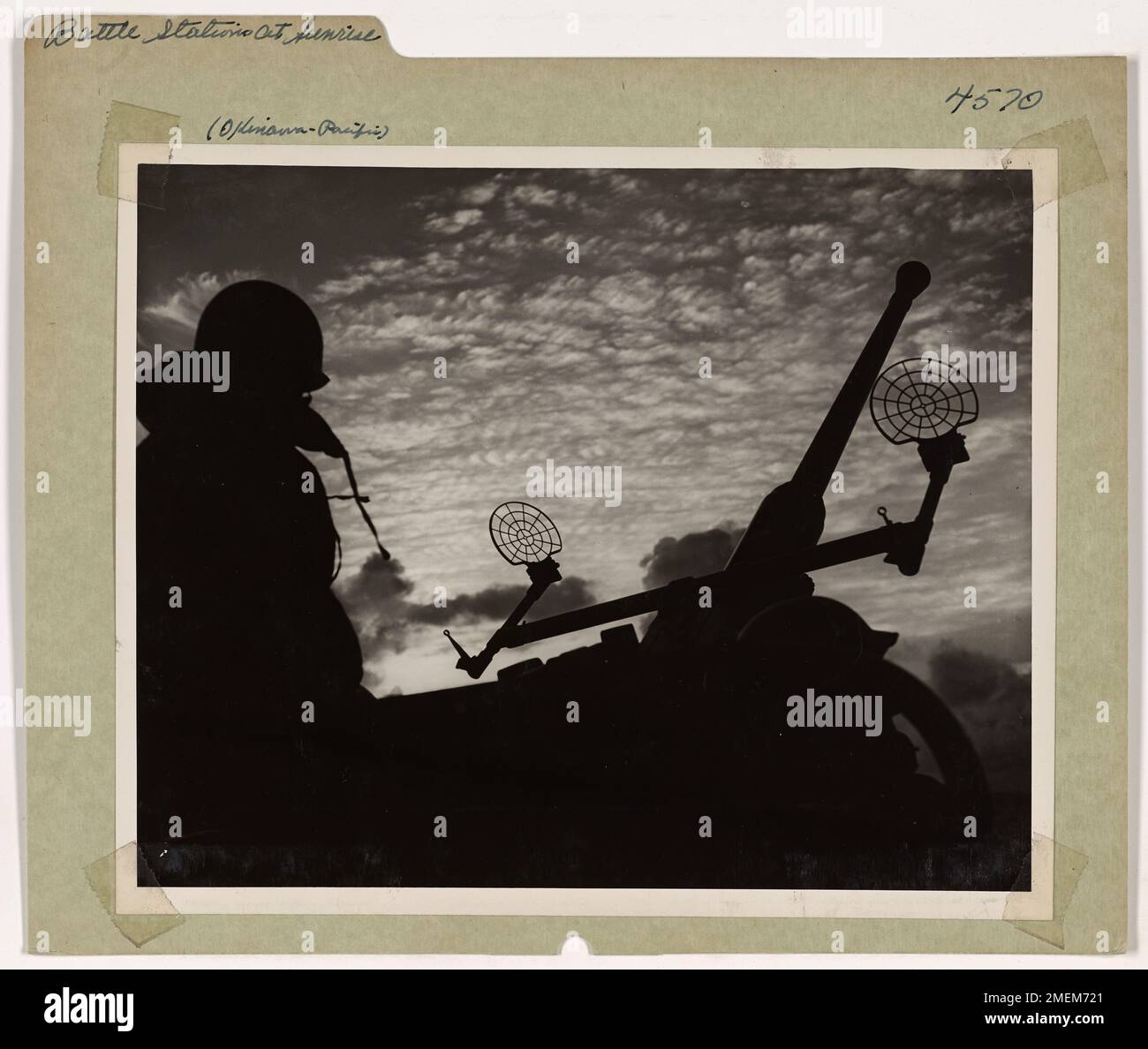 Battle Stations at Sunrise. Coast Guard gunners are alerted at their guns as a Coast Guard-manned LST moves through dangerous waters in the west Pacific. These carriers of vital war machinery are vigilantly protected around the clock against the dangers of surprise attacks by Jap bombers. This Coast Guardsman enjoys the golden fleece in the morning sky and yet knows that out of that beauty enemy planes may roar at any moment. Stock Photo